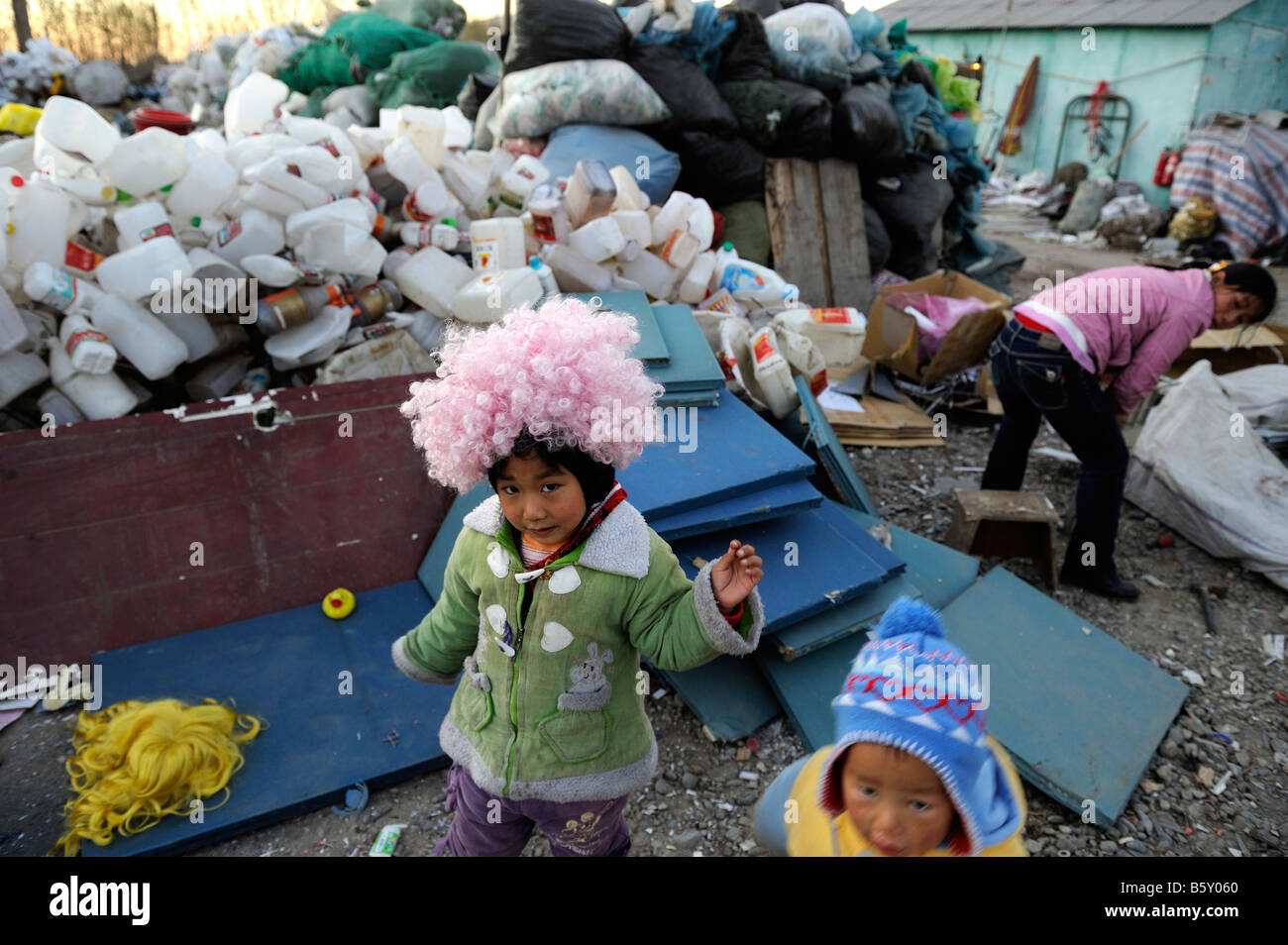 Una bambina indossa una parrucca raccolti dal cestino in corrispondenza di una stazione di recupero in città dongxiaokou nella periferia nord di Pechino, Cina Foto Stock