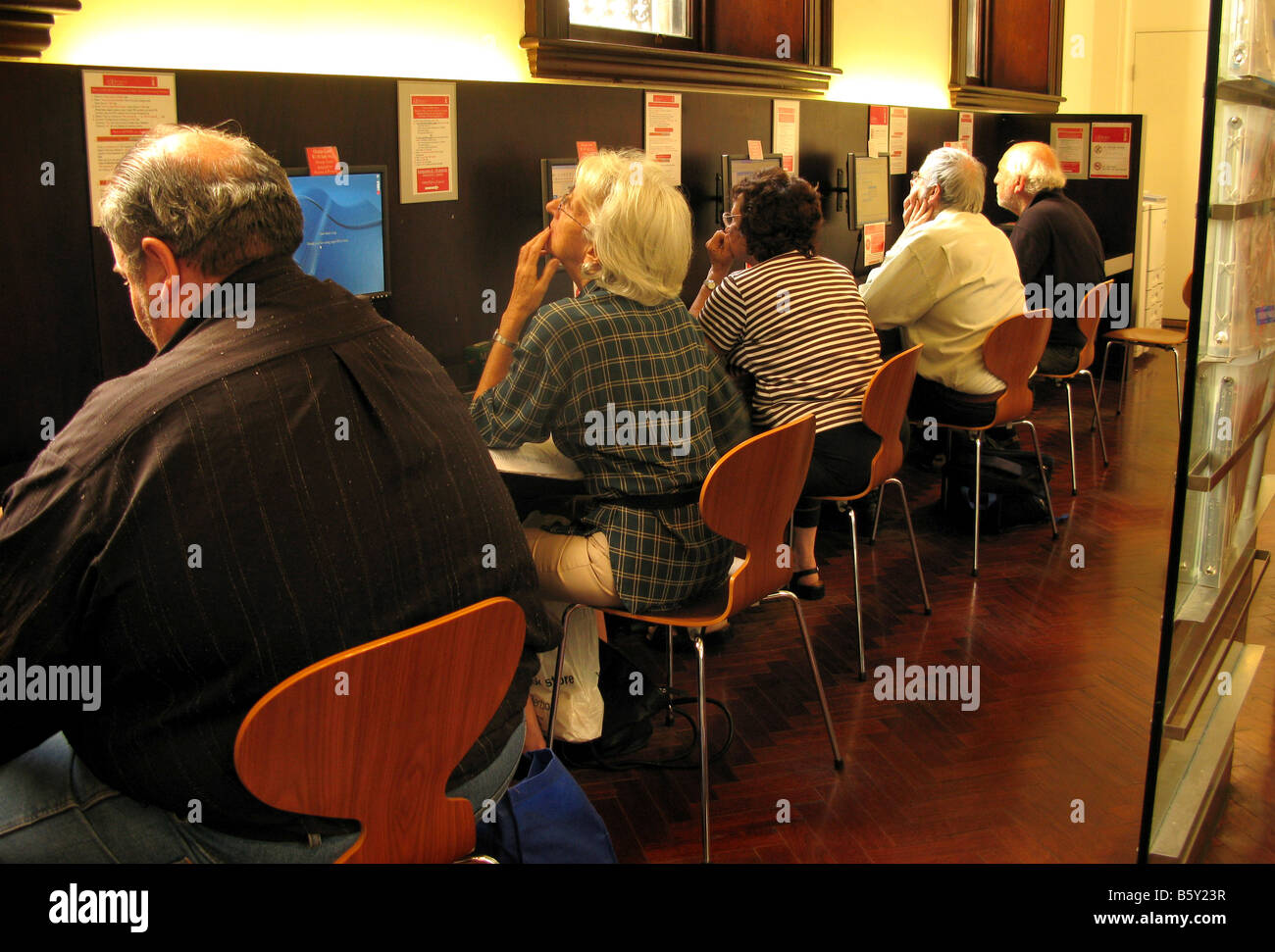 Una camera di mezza età a vecchie persone usano Internet in una biblioteca pubblica Foto Stock