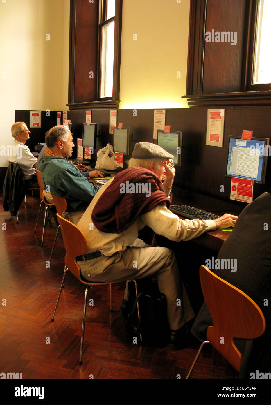 Una camera di mezza età a vecchie persone usano Internet in una biblioteca pubblica Foto Stock