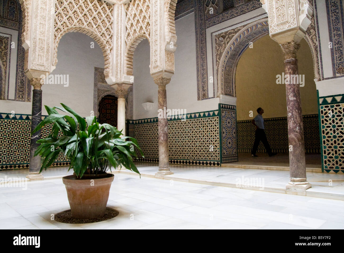 Un turista passeggiate oltre il Patio de las Munecas, decorato con piastrelle colorate e stucco di arabeschi, nell'Alcazar, Sevilla, Andalusia, Spagna. Foto Stock