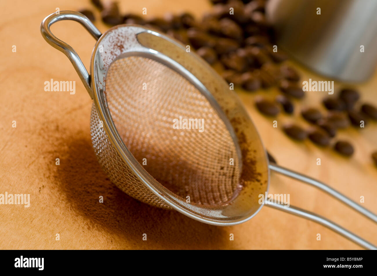 Del filtro in acciaio inox con polvere di cacao su legno Foto Stock