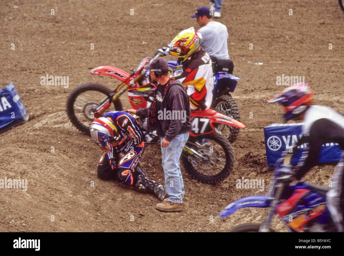 Sicurezza crewman sorge oltre il pilota ferito durante la gara di motocross. Foto Stock