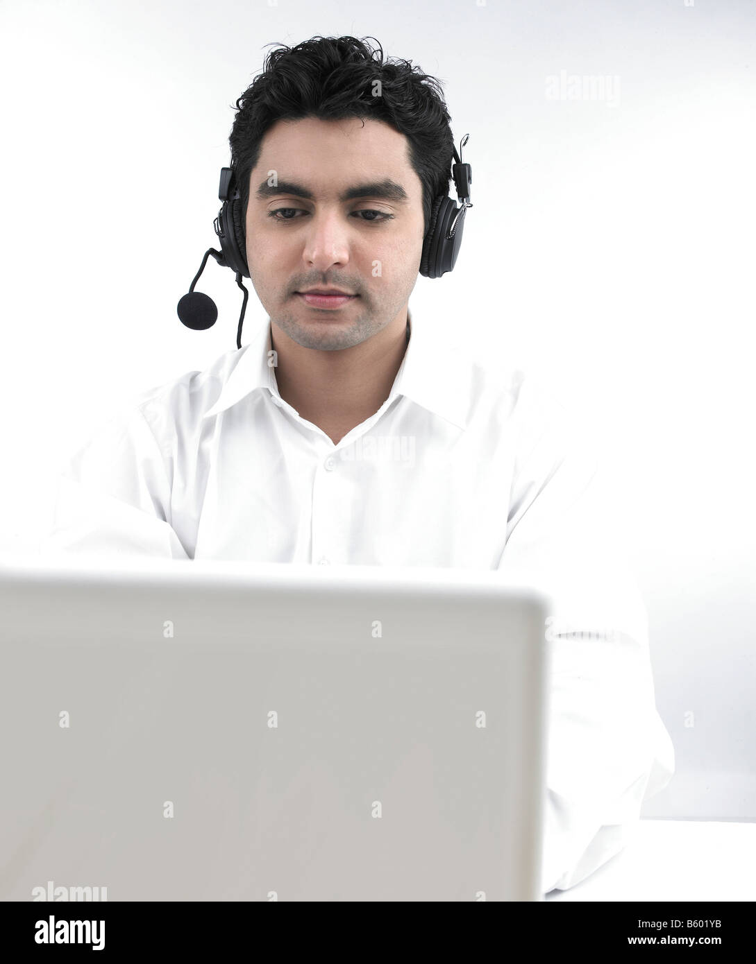 Uomo asiatico lavorando sul suo laptop che indossa le sue cuffie Foto Stock