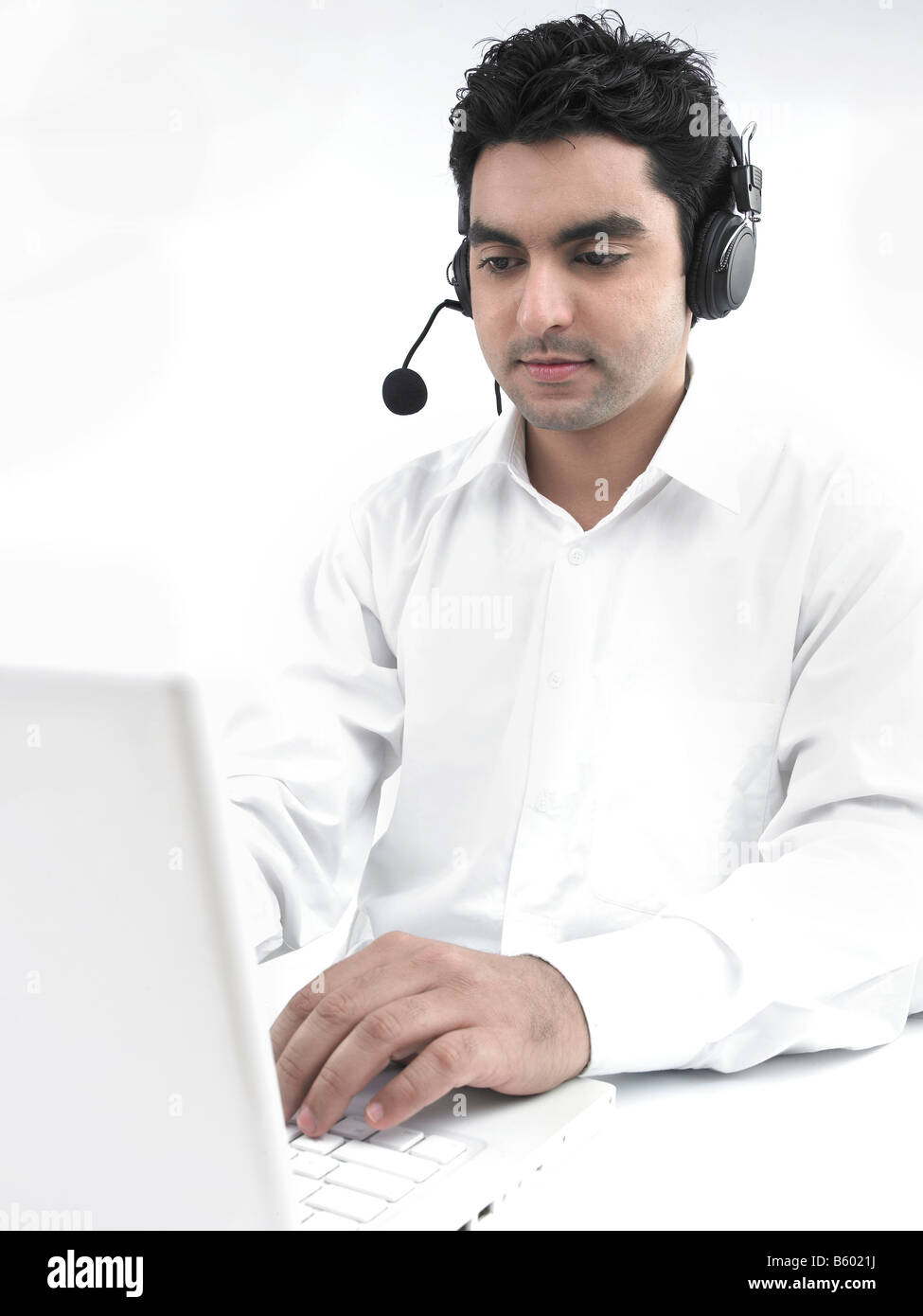 Uomo asiatico lavorando sul suo laptop che indossa le sue cuffie Foto Stock
