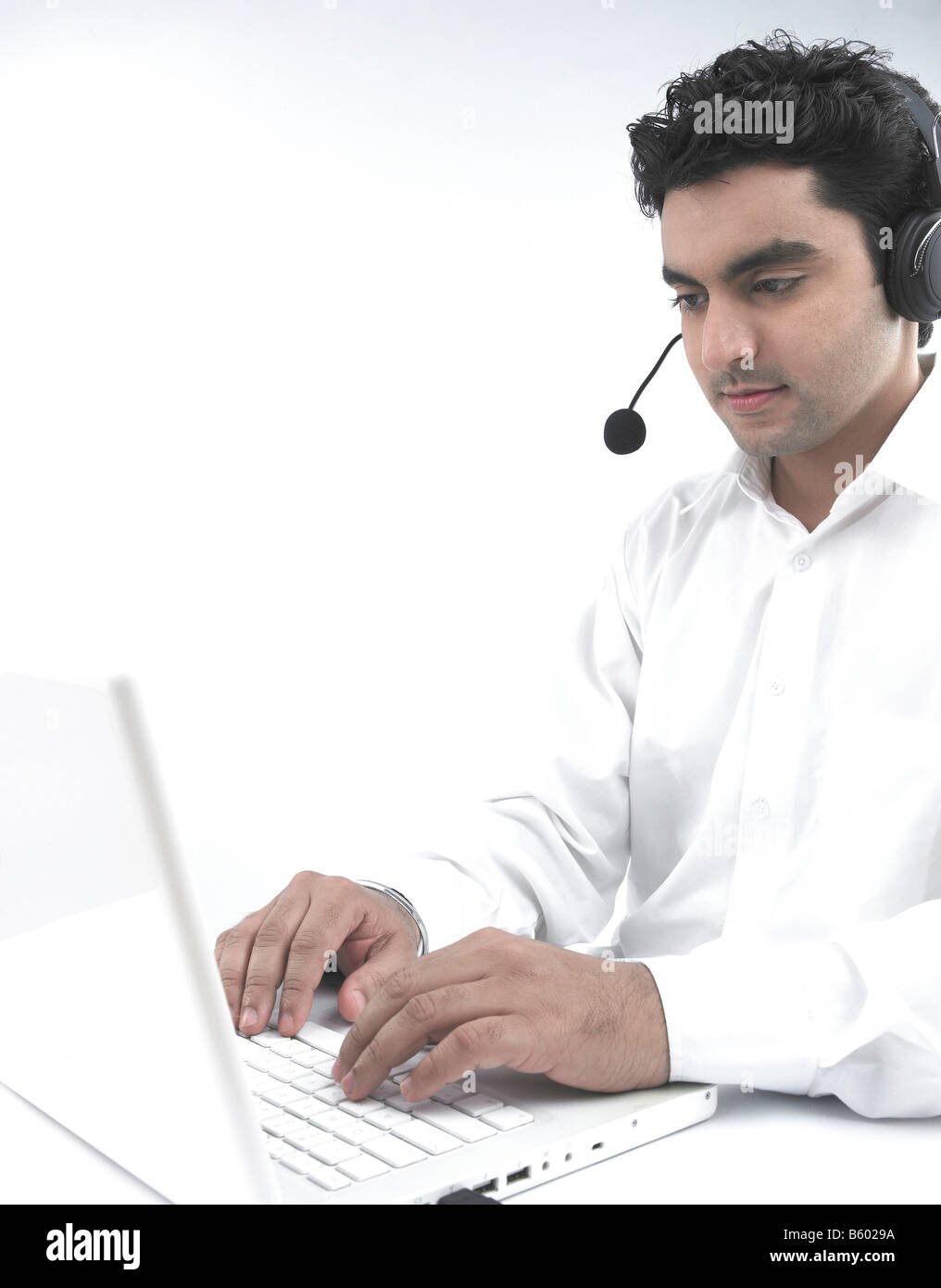 Uomo asiatico lavorando sul suo laptop che indossa le sue cuffie Foto Stock