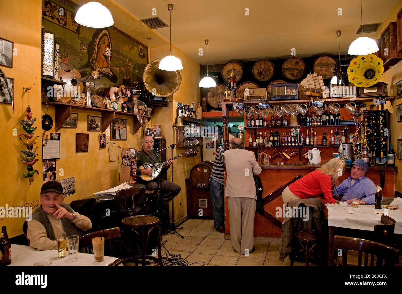 All'interno di una caffetteria locale nel porto del Pireo caos musica sitar bere cafe bar uomo donna Atene Grecia greco Foto Stock