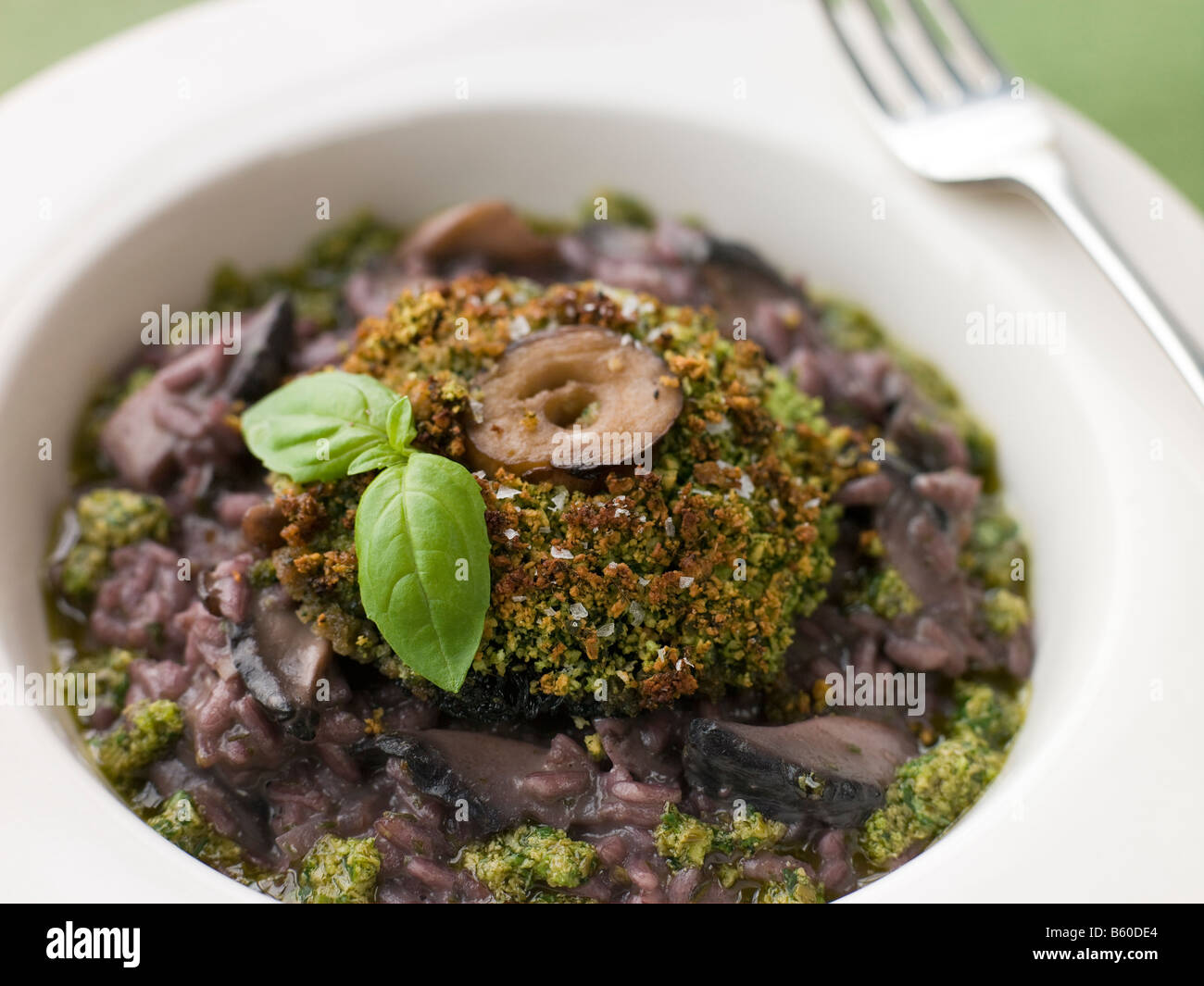 In crosta di erbe Portabello fungo con risotto al vino rosso e Pesto Dressing Foto Stock