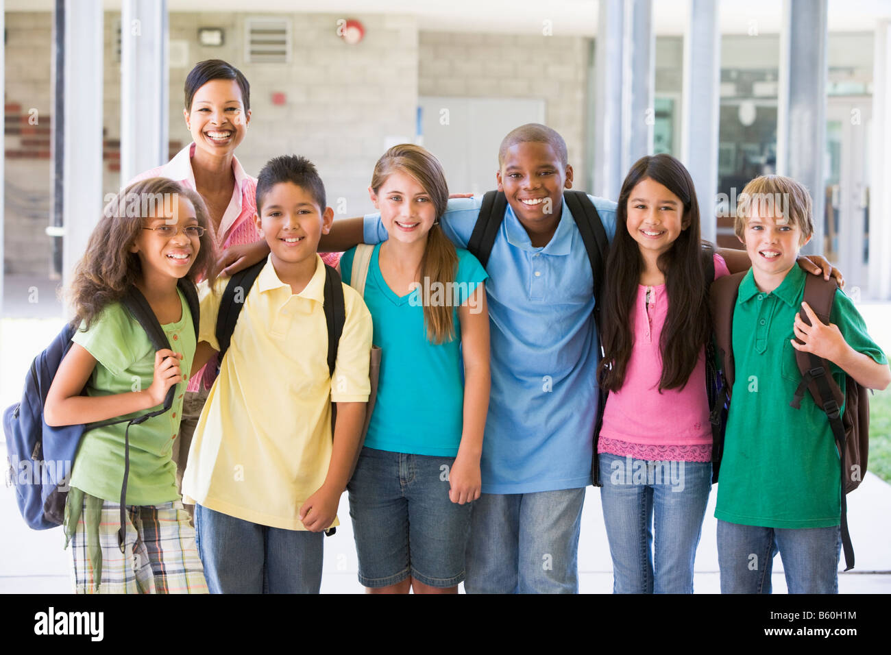Sei studenti in piedi al di fuori della scuola con l'insegnante Foto Stock