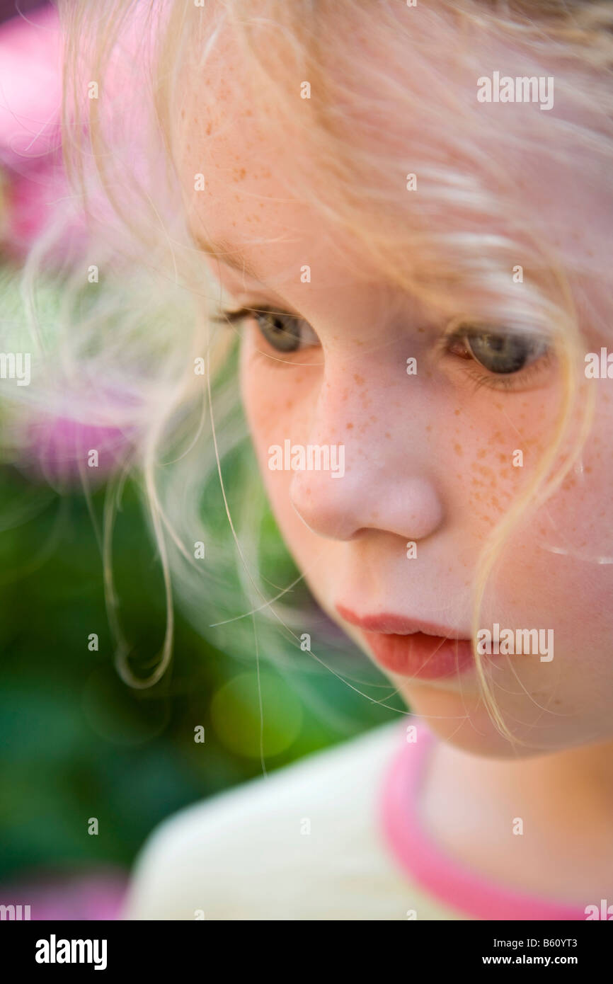 Ritratto di una ragazza freckled, 5-10 anni, in un giardino di fiori Foto Stock