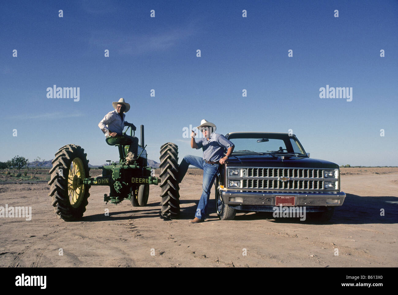 L'agricoltore e artista Carl Clapp, in un pickup parla di un immigrato messicano salariato agricolo su un trattore John Deere sul suo cotone agriturismo vicino a Phoenix, in Arizona Foto Stock