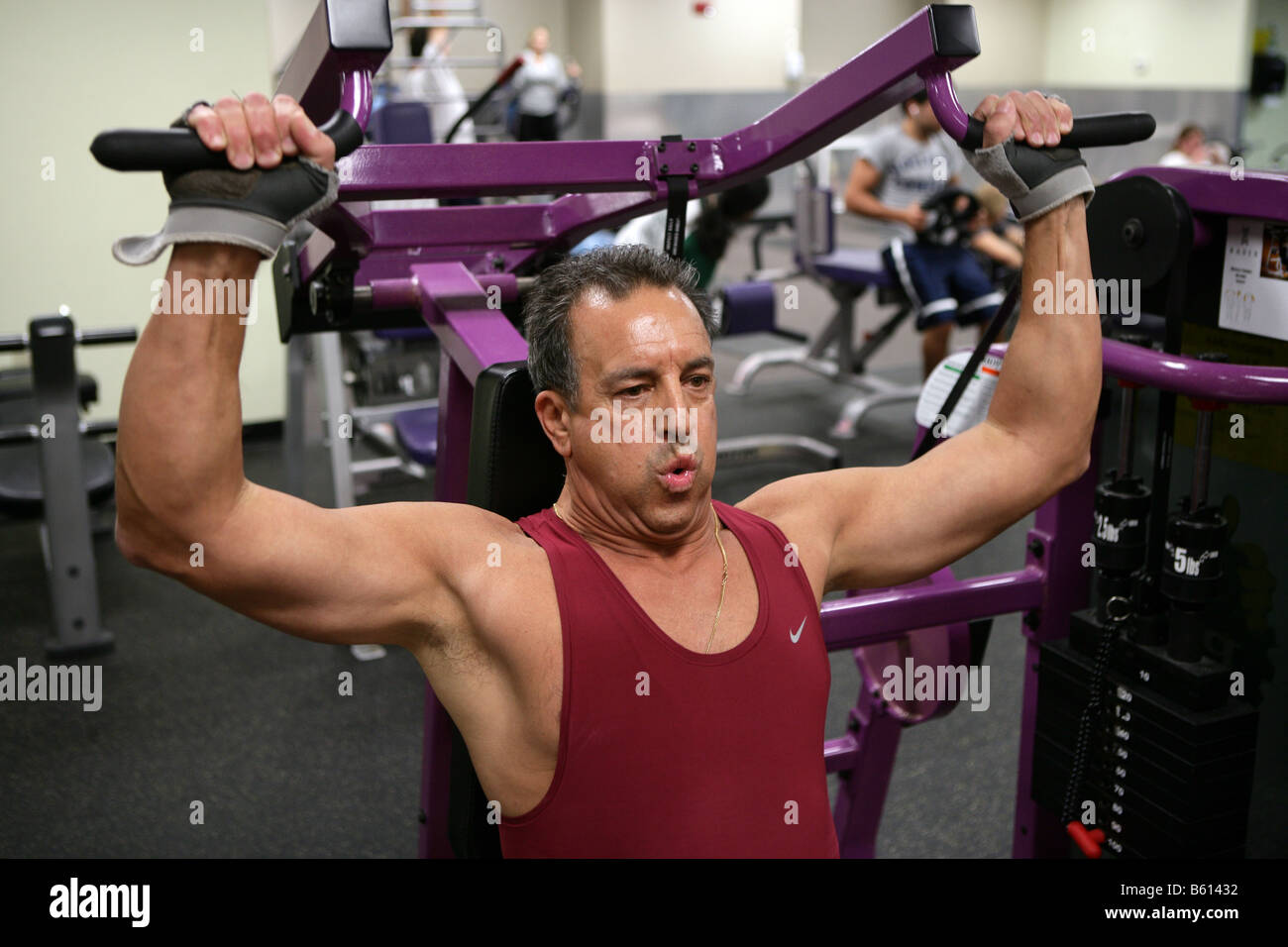 Un 61-anno-vecchio uomo lavora in una palestra. L'uomo, che ha una storia familiare di malattia cardiaca funziona a migliorare le sue condizioni di salute. Foto Stock