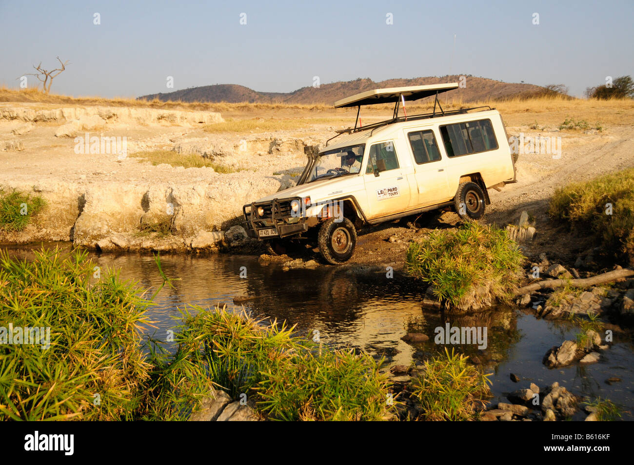 Veicolo che attraversa il corso di un fiume, Parco Nazionale del Serengeti, Tanzania Africa Foto Stock