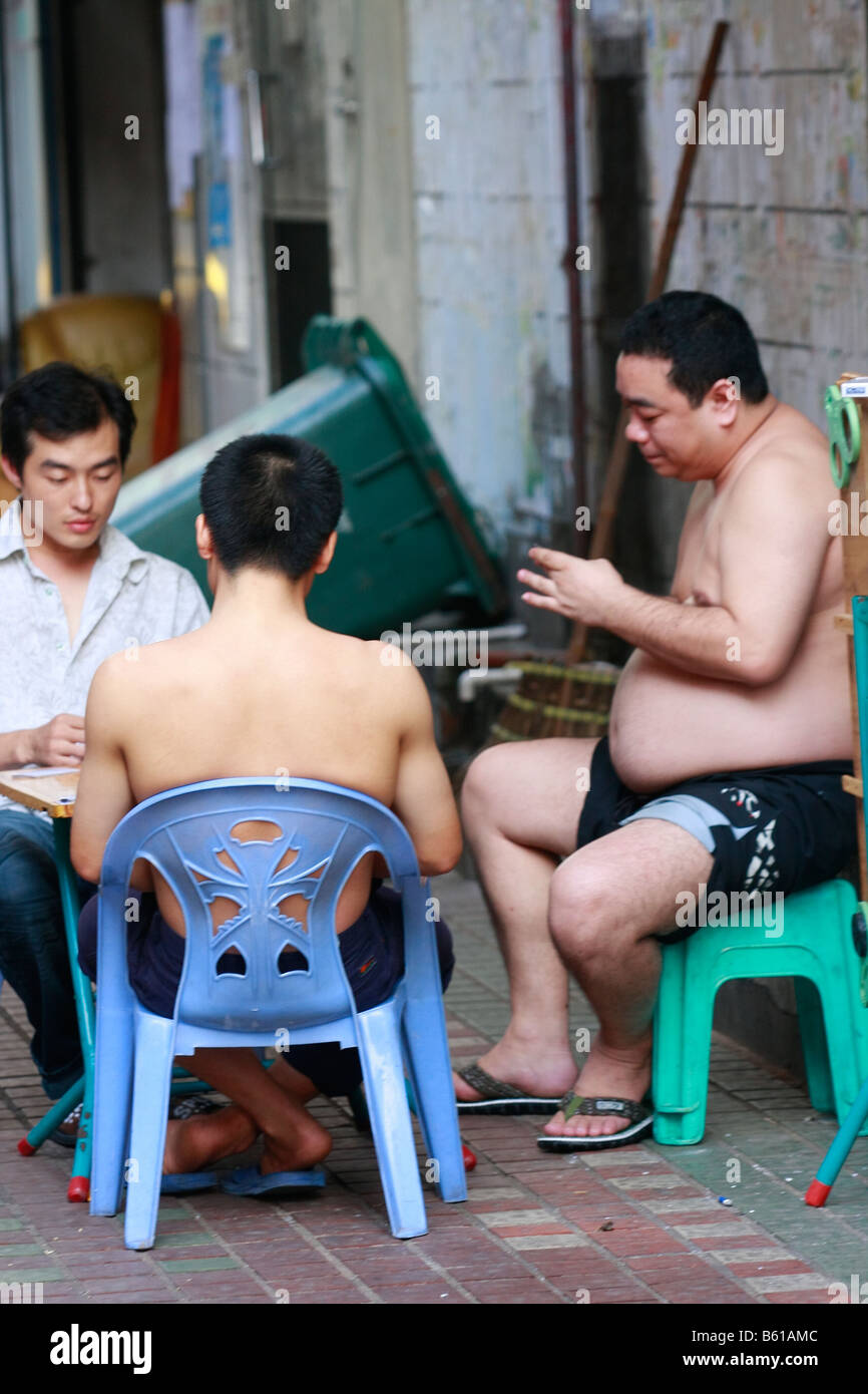 Gli uomini cinesi godendo di un gioco di carte nel vicolo Foto Stock