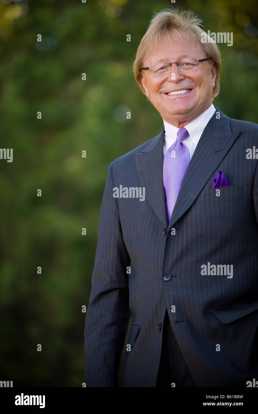 50 anno vecchio business man standing esterno, indossa una tuta e cravatta, sorridente e guardando la telecamera. Foto Stock
