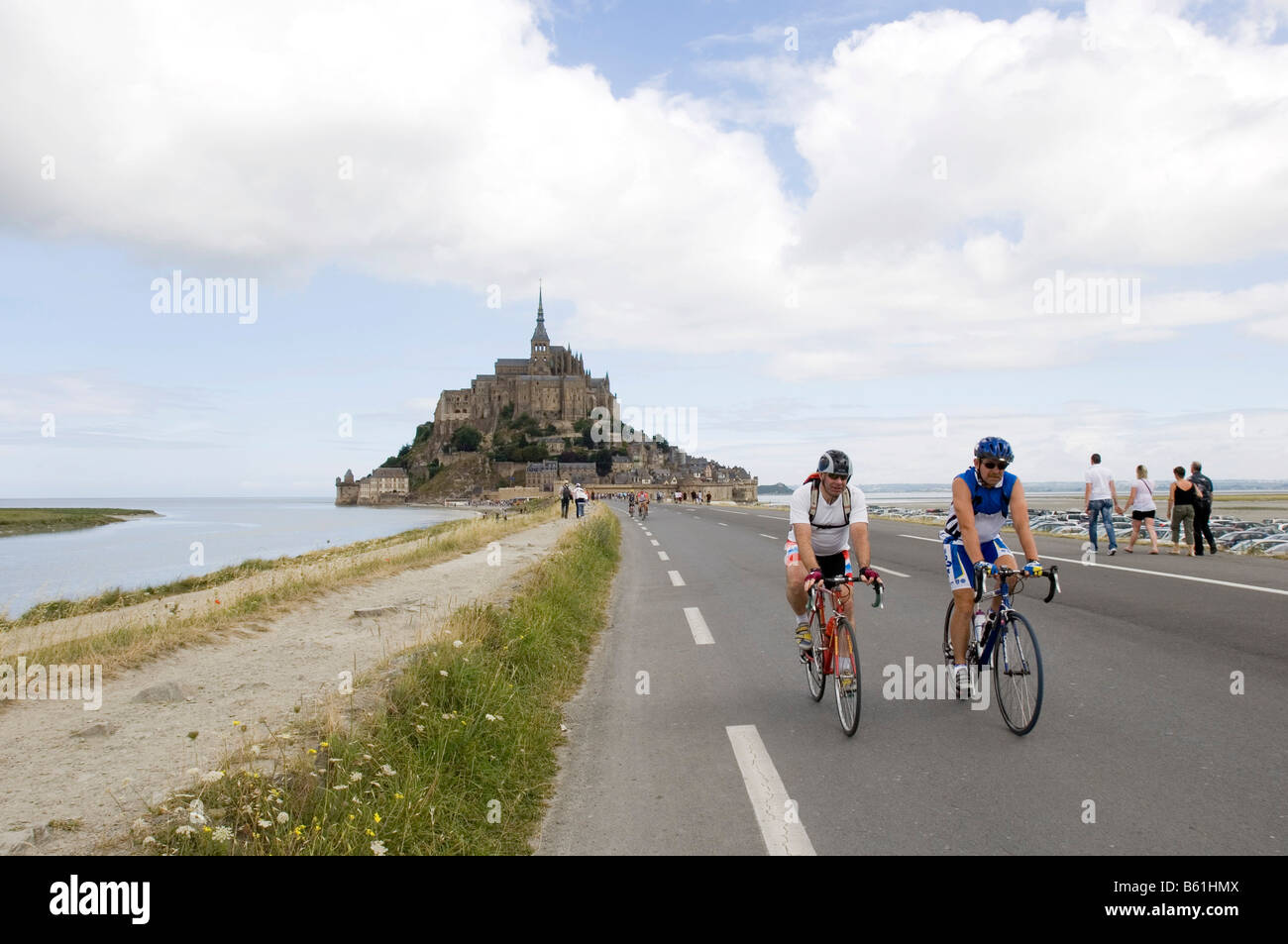 Turisti in bicicletta nella parte anteriore del Mont Saint Michel, in Normandia, Francia, Europa Foto Stock