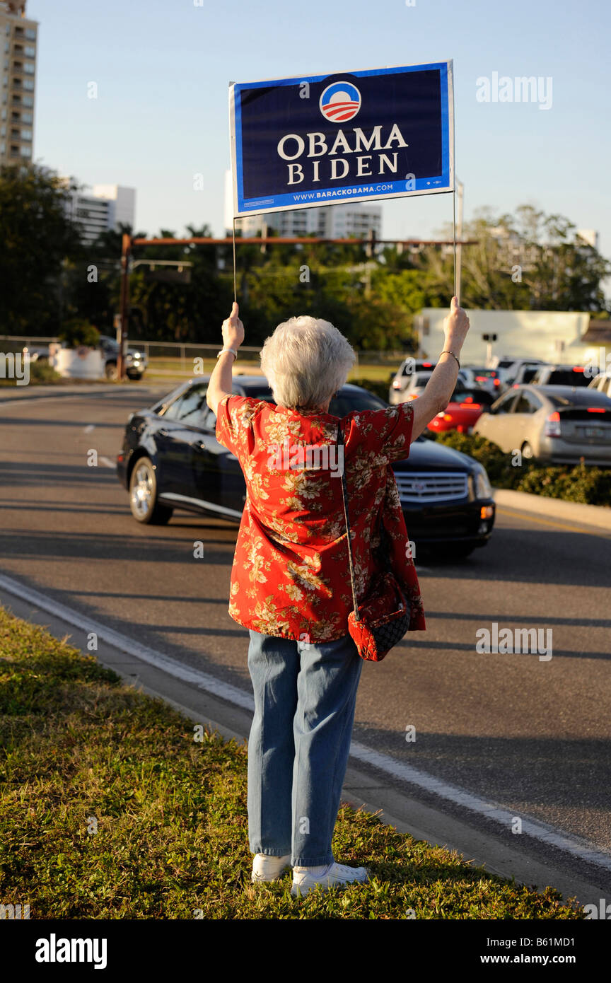Femmina senior citizen sostenitore mostra segni di Barack Obama per il presidente sulla strada trafficata Foto Stock