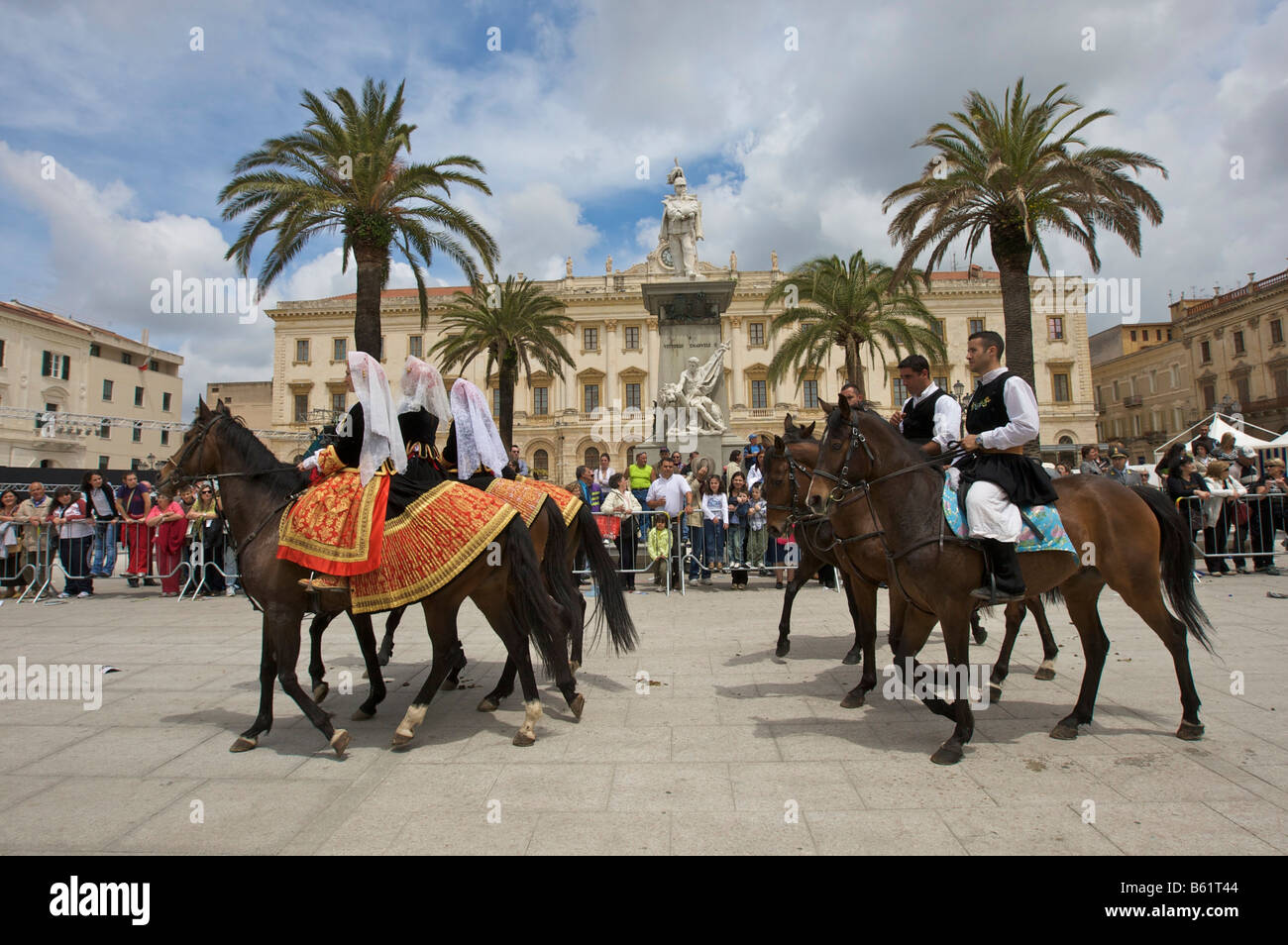Gli uomini e le donne a cavallo indossando costumi tradizionali presso la Cavalcata Sarda sfilata sulla Piazza Italia a Sassari, S Foto Stock
