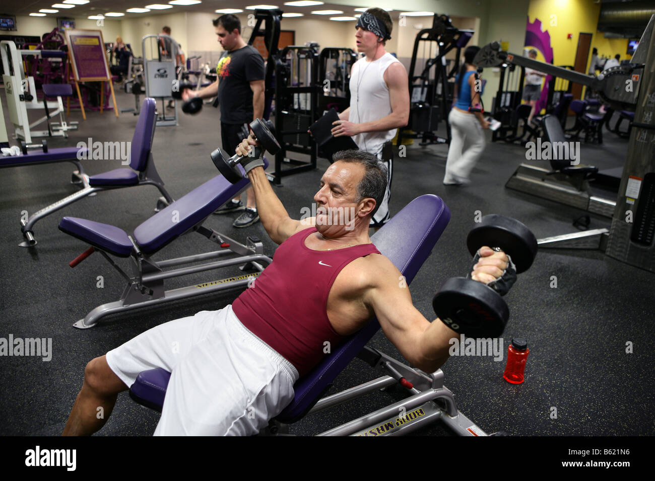 Un 61-anno-vecchio uomo lavora in una palestra. L'uomo, che ha una storia familiare di malattia cardiaca funziona a migliorare le sue condizioni di salute. Foto Stock