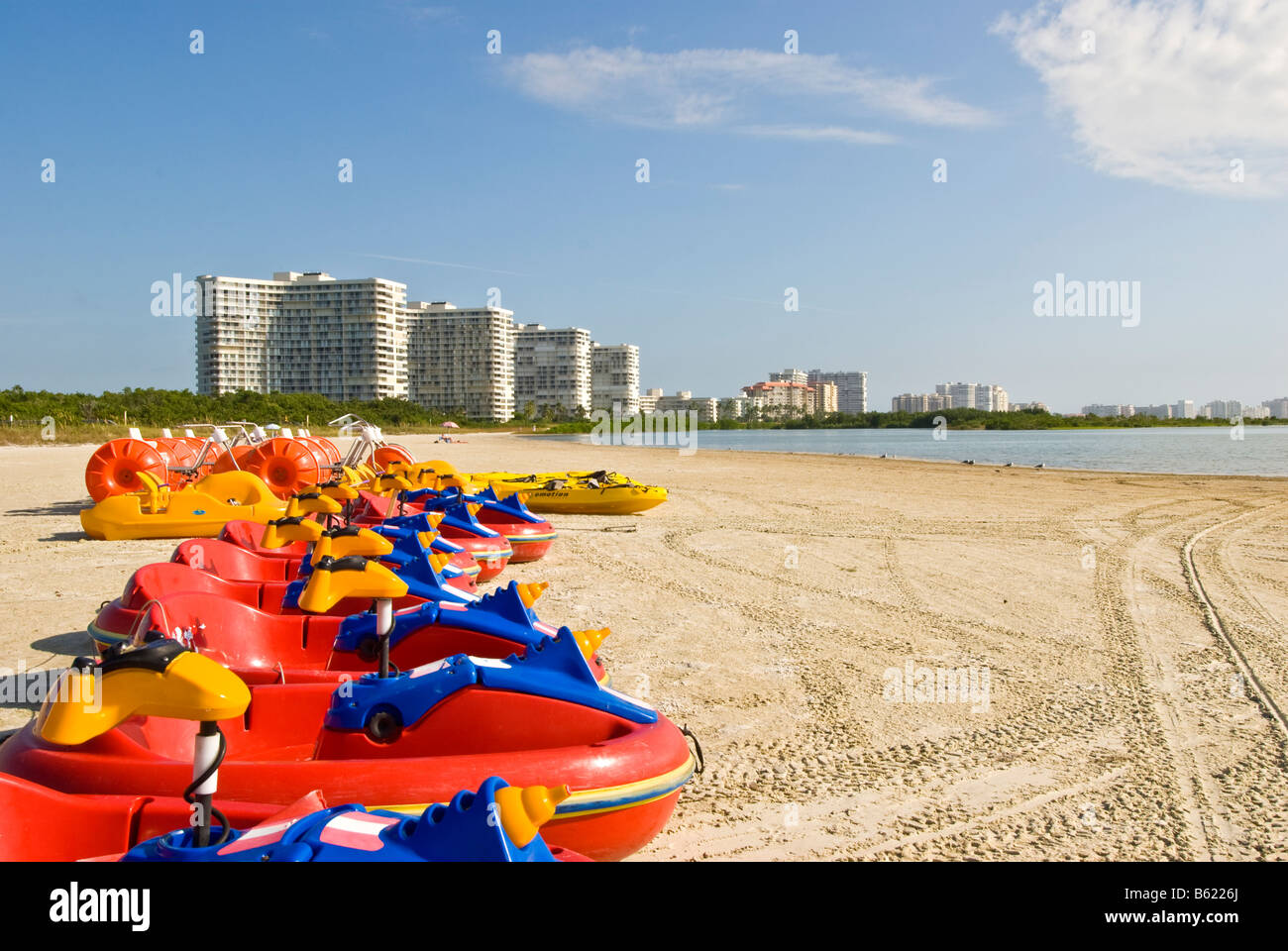 Coda di Tiger Beach Marco Island Florida vivacemente colorate di rosso barche di alta crescita condominiums in background Foto Stock