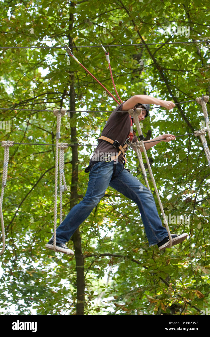 Ragazzo, ca. 16, equilibratura su funi, ca. Alta 10 metri, infilate tra alberi, Kletterwald, Neroberg, Wiesbaden, Hesse, Germania, UE Foto Stock