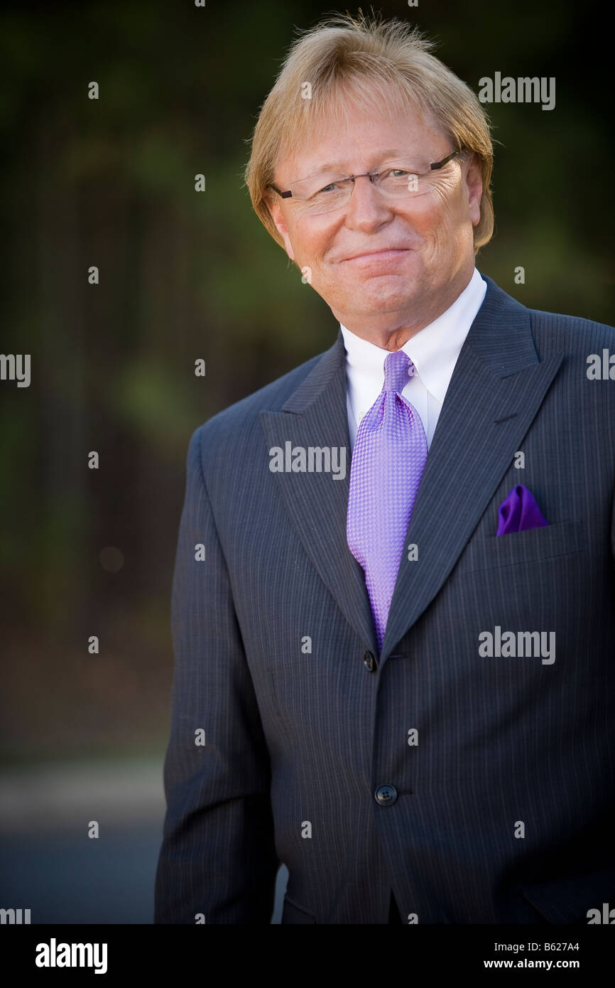 50 anno vecchio business man standing esterno, indossa una tuta e cravatta, sorridente e guardando la telecamera. Foto Stock