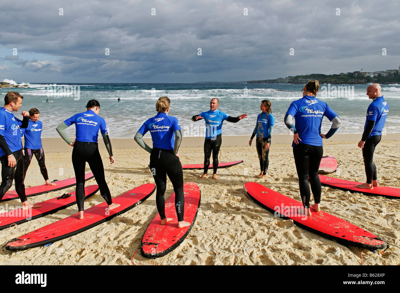 Surfers l'ascolto delle istruzioni durante lezioni di surf a Bondi Beach, Sydney, Nuovo Galles del Sud, Australia Foto Stock