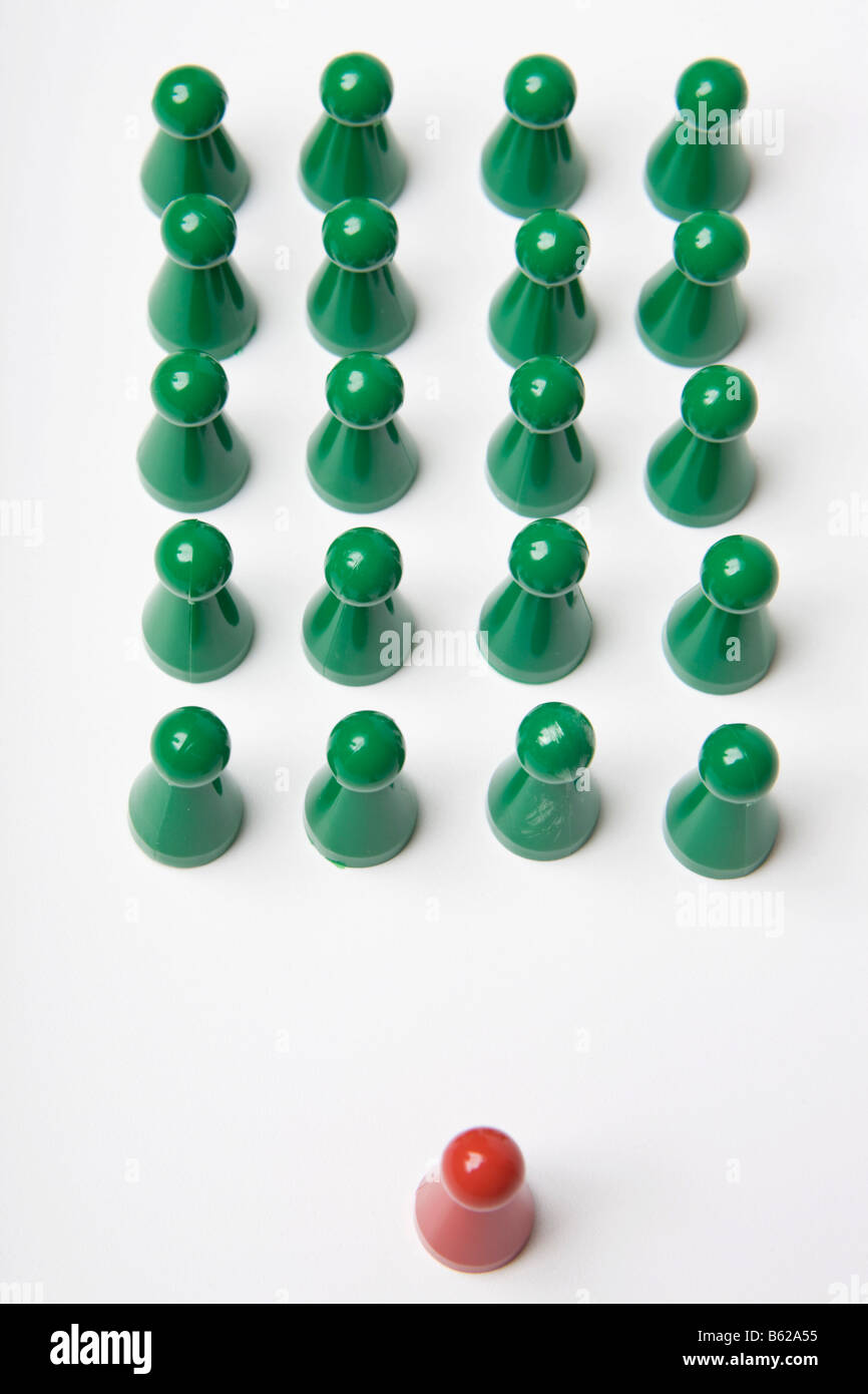 Verde di pezzi di gioco in piedi ordinati insieme con un unico red gaming pezzo davanti, simbolico di in rango e file Foto Stock