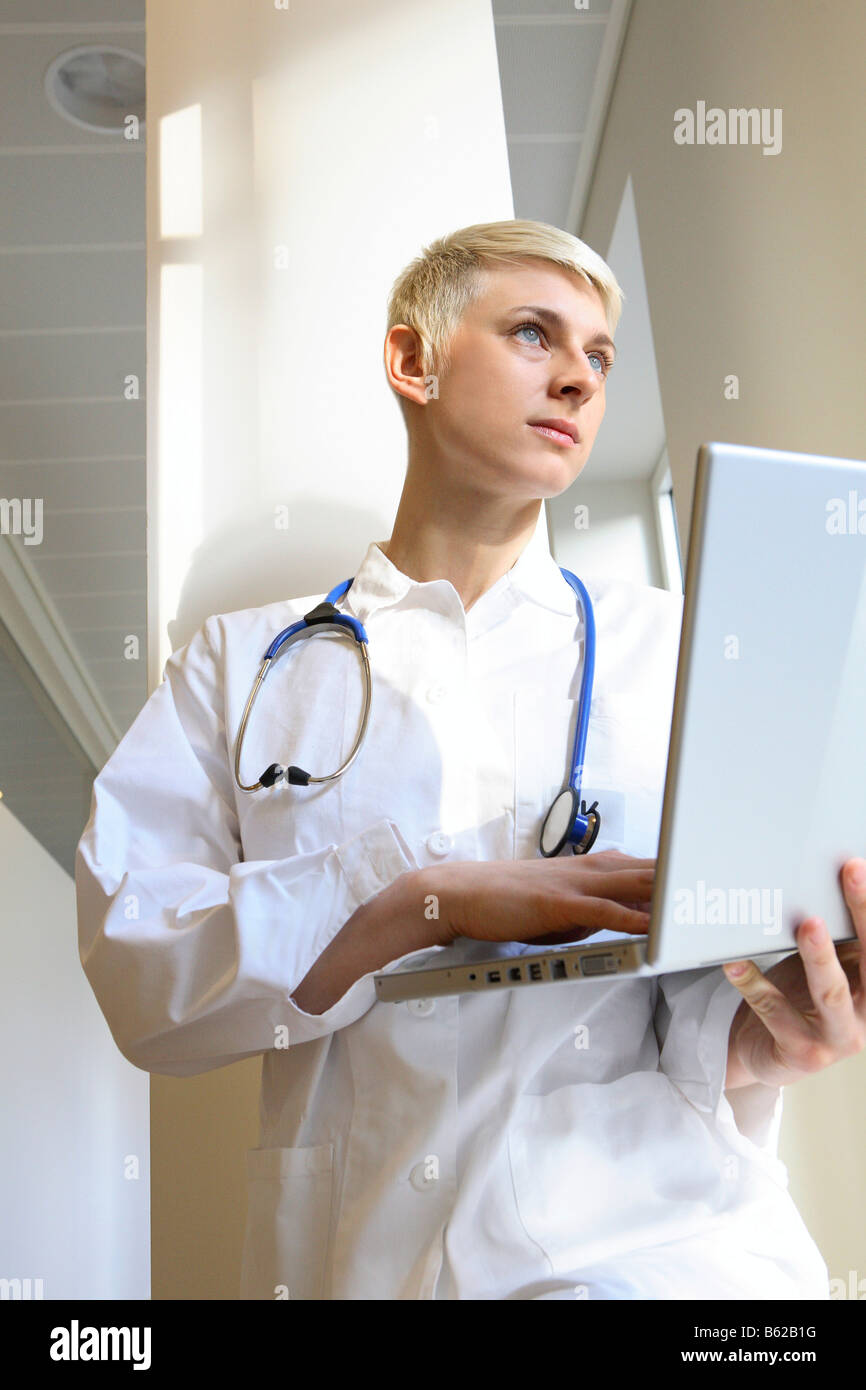 Giovane medico con uno stetoscopio al lavoro su un notebook Foto Stock