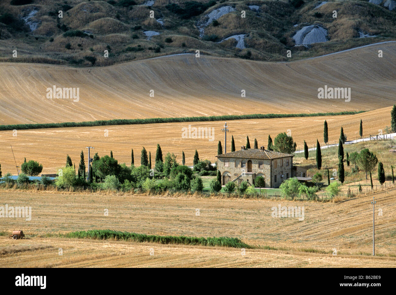 Cascina tra raccolte di campi di grano, Le Crete vicino Pievina, in provincia di Siena, Toscana, Italia, Europa Foto Stock