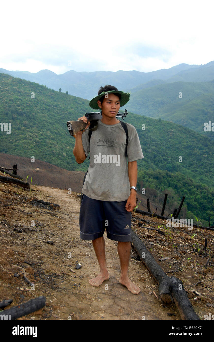 Il laotiano uomo che porta in mano una pistola in montagna attraverso terra cancellata da una barra e masterizzare, Phongsali Provincia, Laos, sud-est asiatico Foto Stock