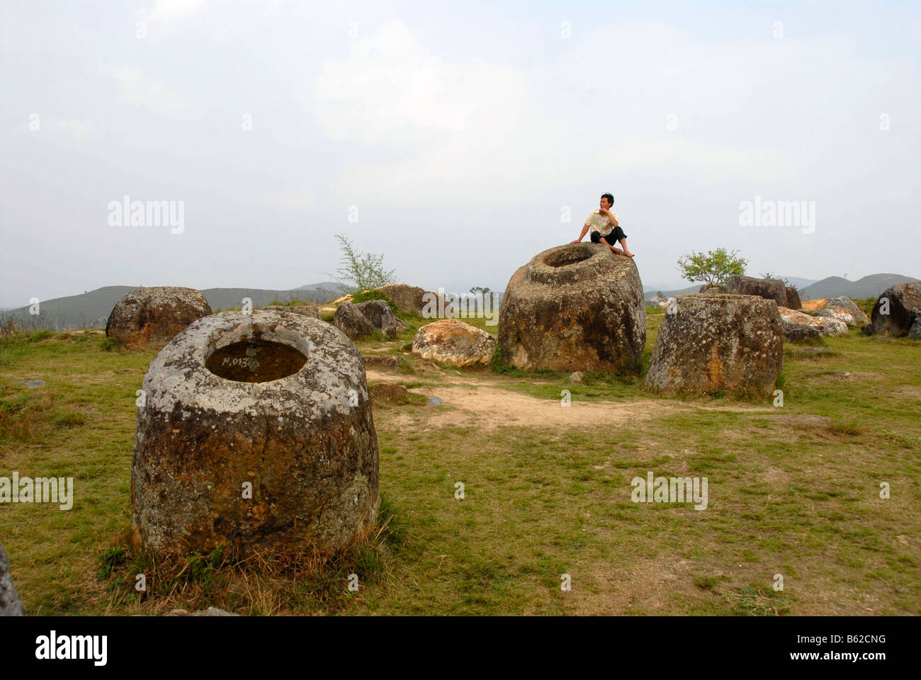 Una persona seduta su uno dei misteriosi bellarmines, Pianura di giare, luogo di scoperta no. 1 (Thong Hai Hin), Xieng Khuang Pr Foto Stock
