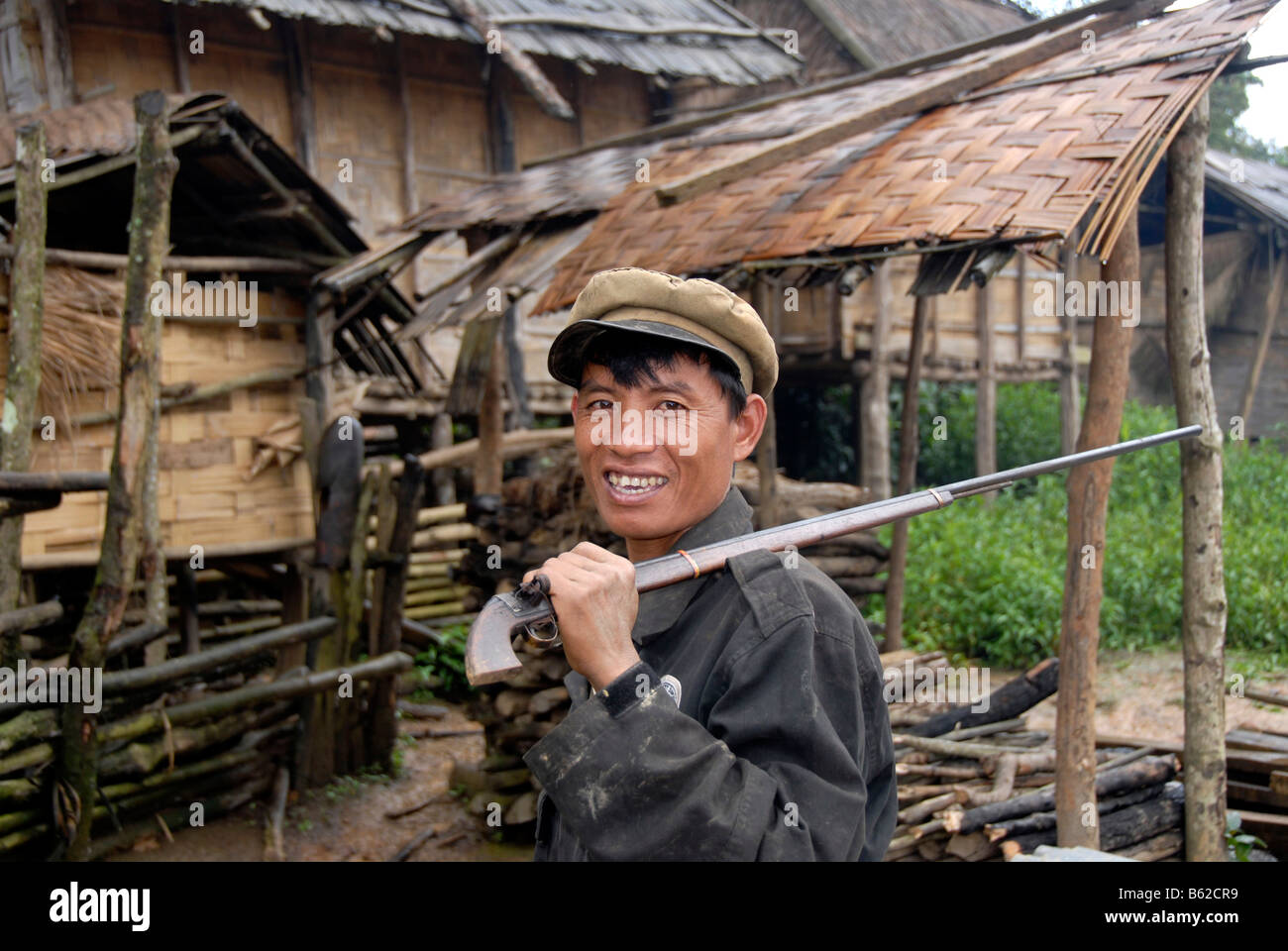 Ritratto di un uomo di Akha A-koo tribù con un berretto e un fucile casualmente espulso attraverso il suo spallamento andando a caccia, vicino Foto Stock