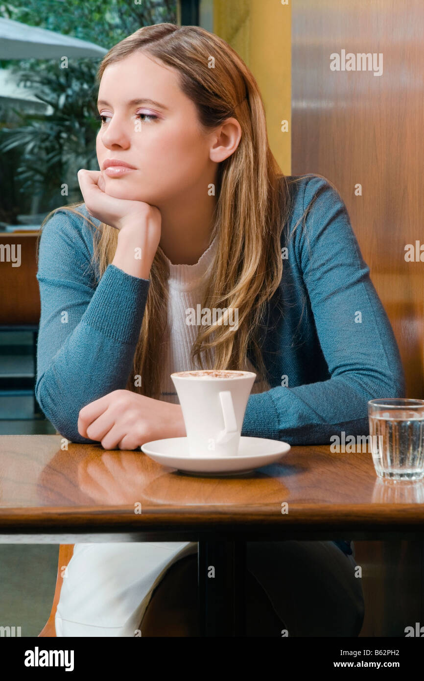 Giovane donna seduta in un cafe e di pensiero Foto Stock