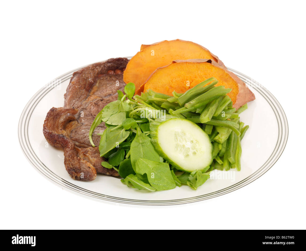 Fresco e salutare la lombata bistecca con patate dolci, fagioli verdi e contorno di insalata isolata contro uno sfondo bianco con n. di persone Foto Stock