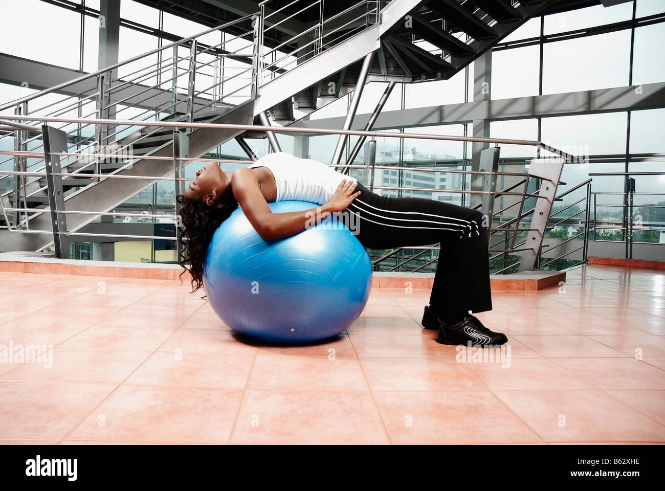 Profilo laterale di una giovane donna che esercitano su di una sfera di fitness Foto Stock