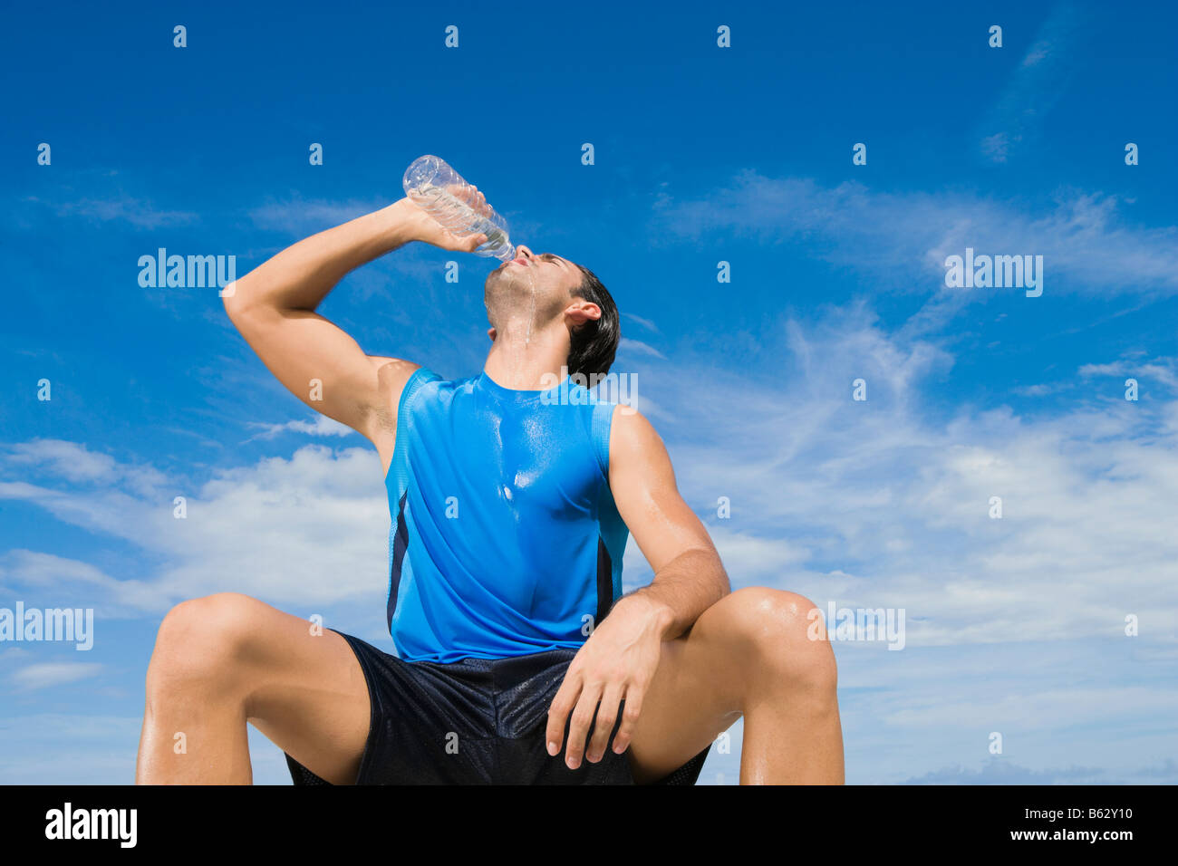 Basso angolo di visione di un giovane uomo di acqua potabile da una bottiglia di acqua Foto Stock