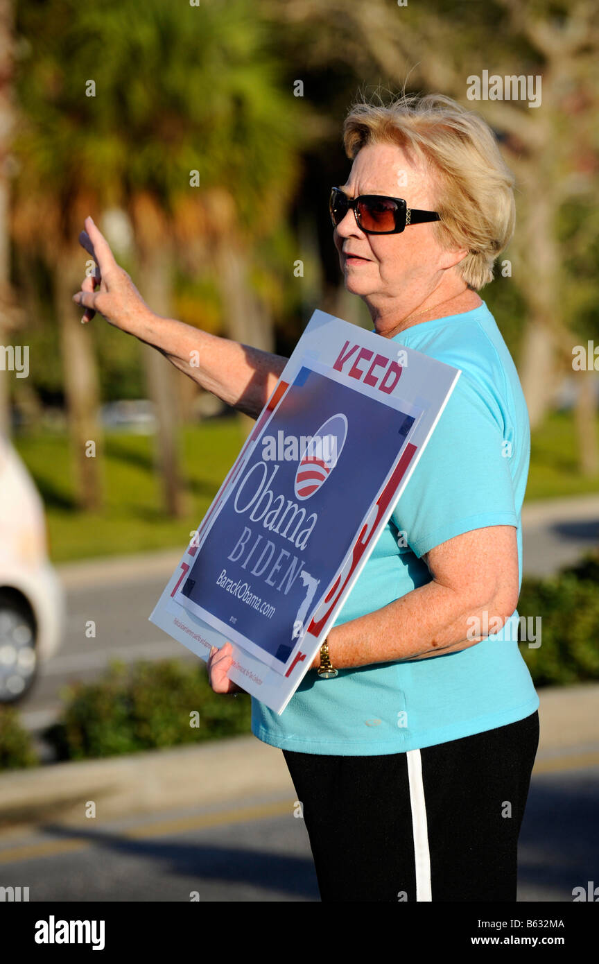 Femmina senior citizen sostenitore mostra segni di Barack Obama per il presidente sulla strada trafficata Foto Stock