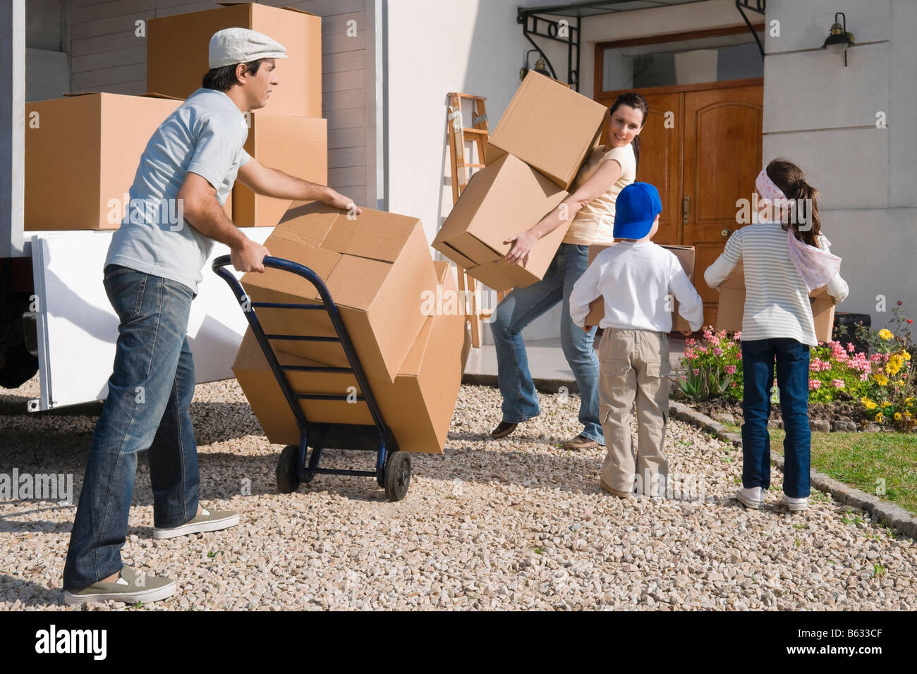 Coppia con i loro figli lo scarico delle merci da un pick-up Foto Stock