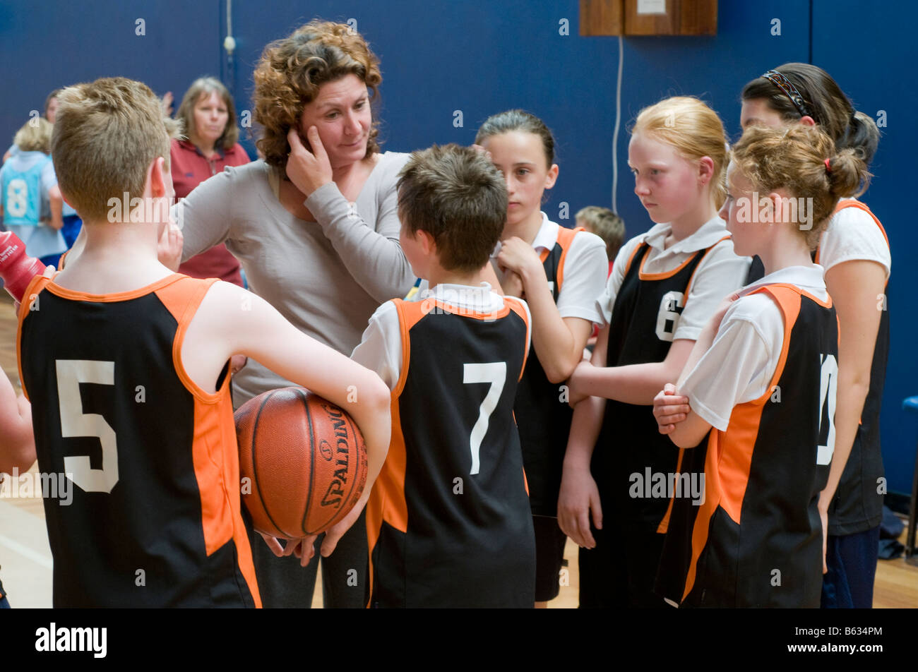 Pullman a discutere di tattiche con i giocatori di un misto di junior scuola primaria squadra di basket Foto Stock