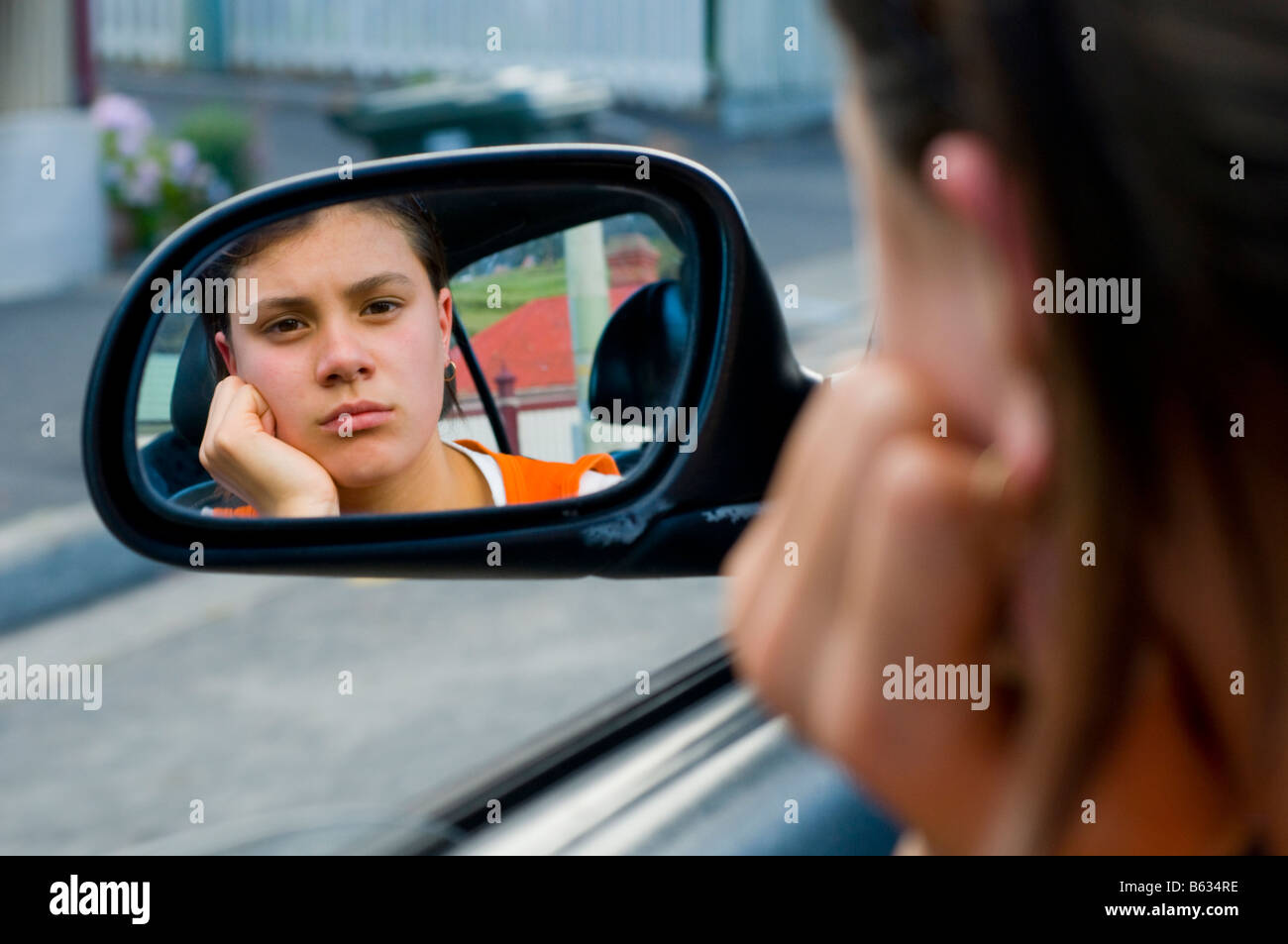 Imbronciato giovane ragazza adolescente a guardare nel retrovisore della macchina Foto Stock