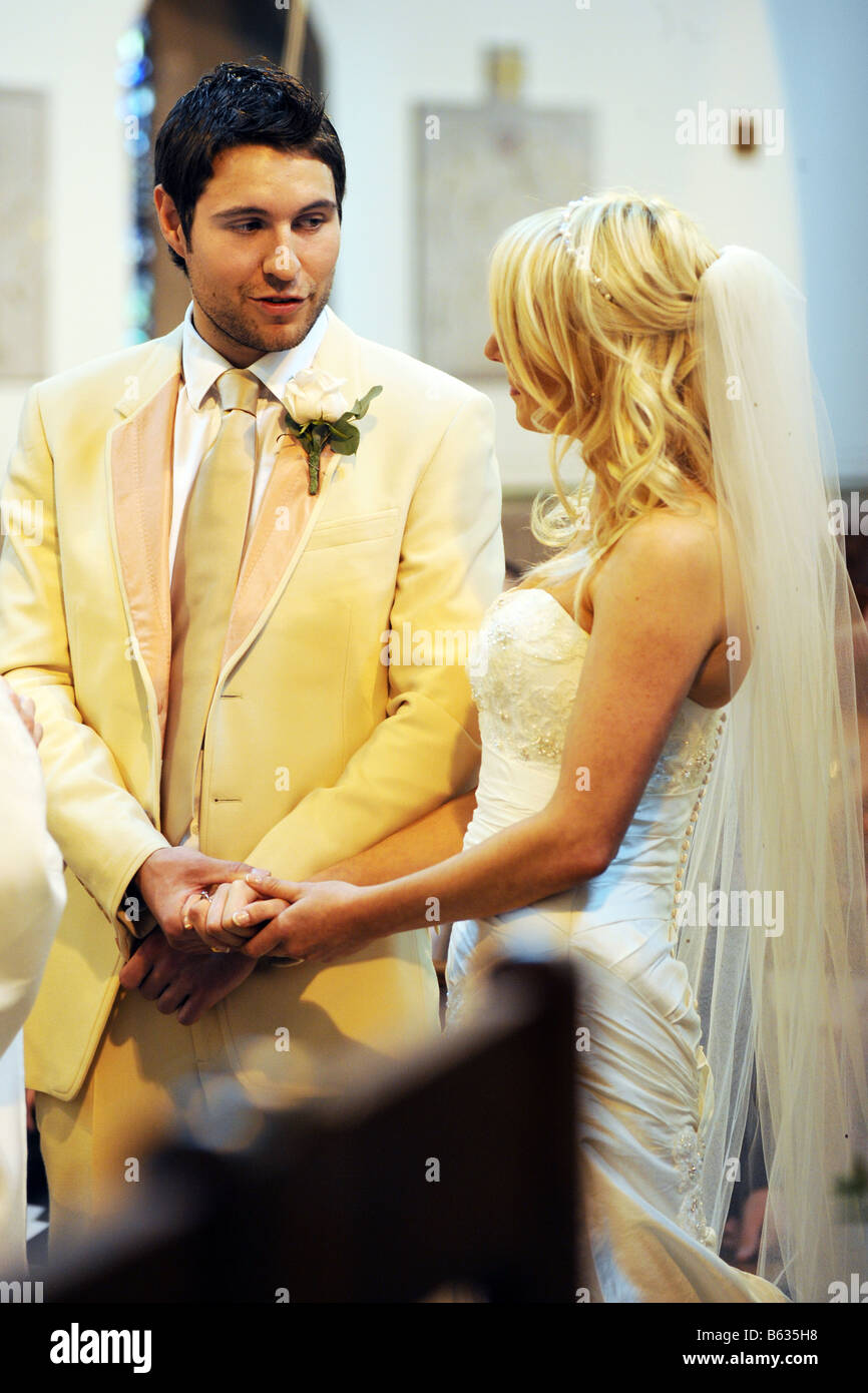 La sposa e lo sposo exhange squilla presso l'altare della chiesa mentre scambiando i loro voti. Foto Stock