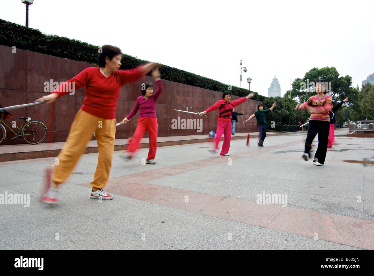 Femmina di praticanti di Tai Chi in motion blur come essi esercitano la loro rituale arti marziali al Bund nelle prime ore del mattino Foto Stock