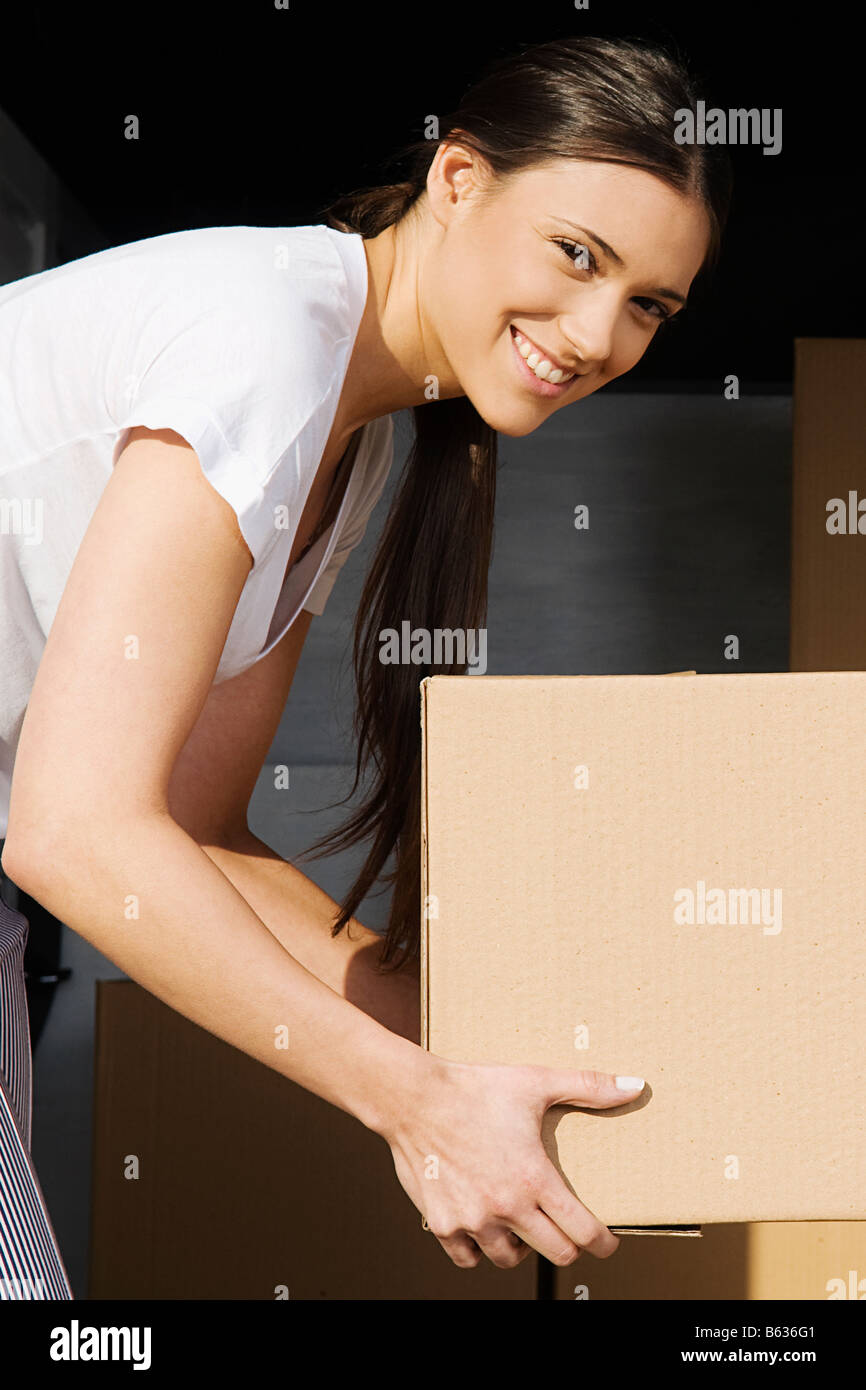 Ritratto di una giovane donna in possesso di una scatola di cartone e sorridente Foto Stock