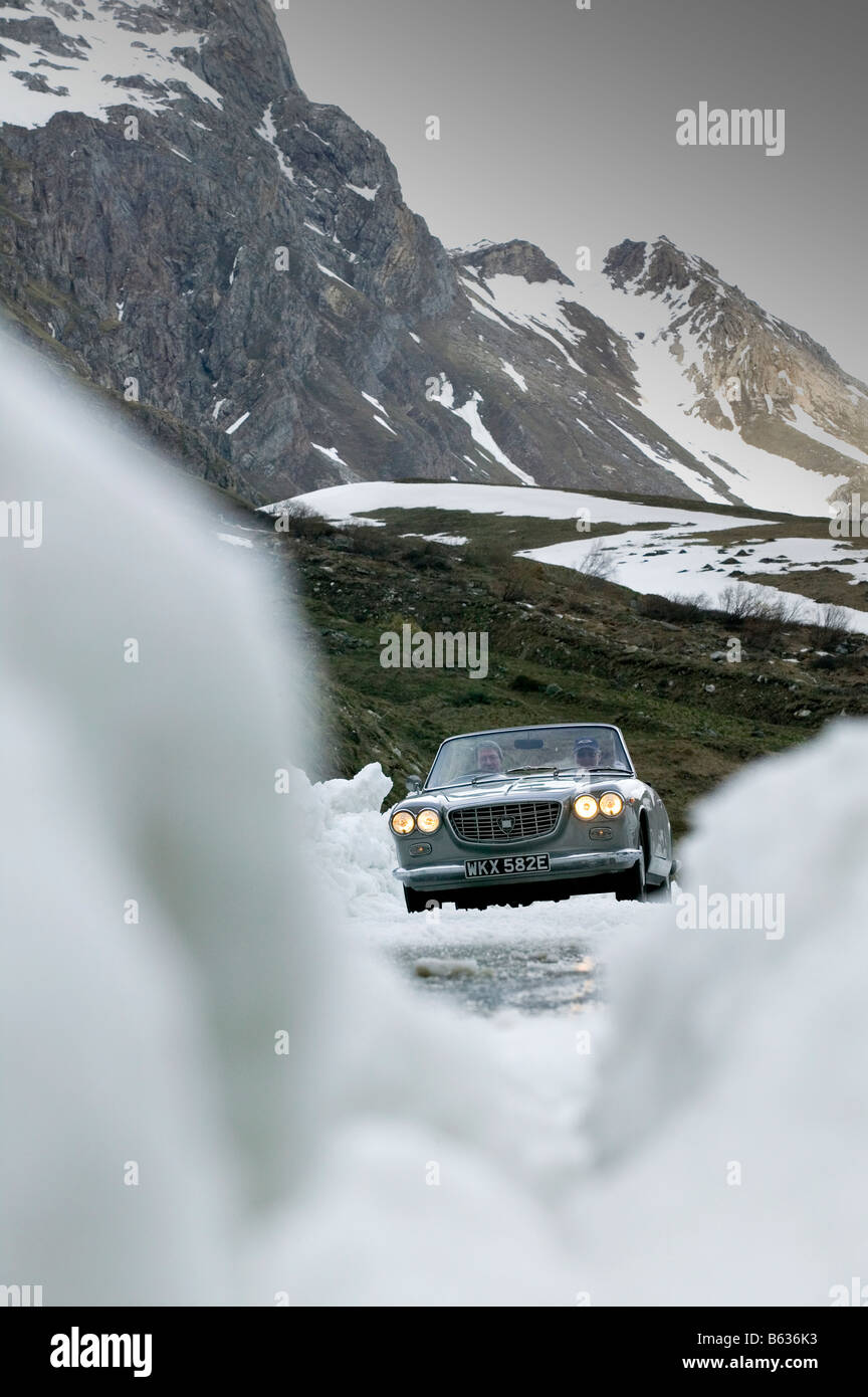 La guida di un auto classica su un passo alpino in inverno Foto Stock