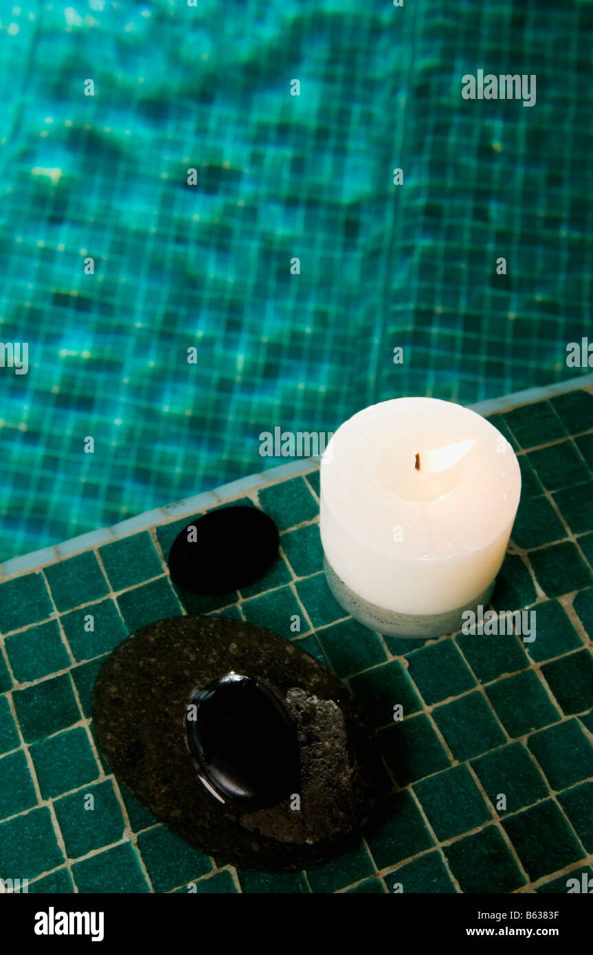 Angolo di alta vista di una candela che brucia e ciottoli a bordo piscina Foto Stock