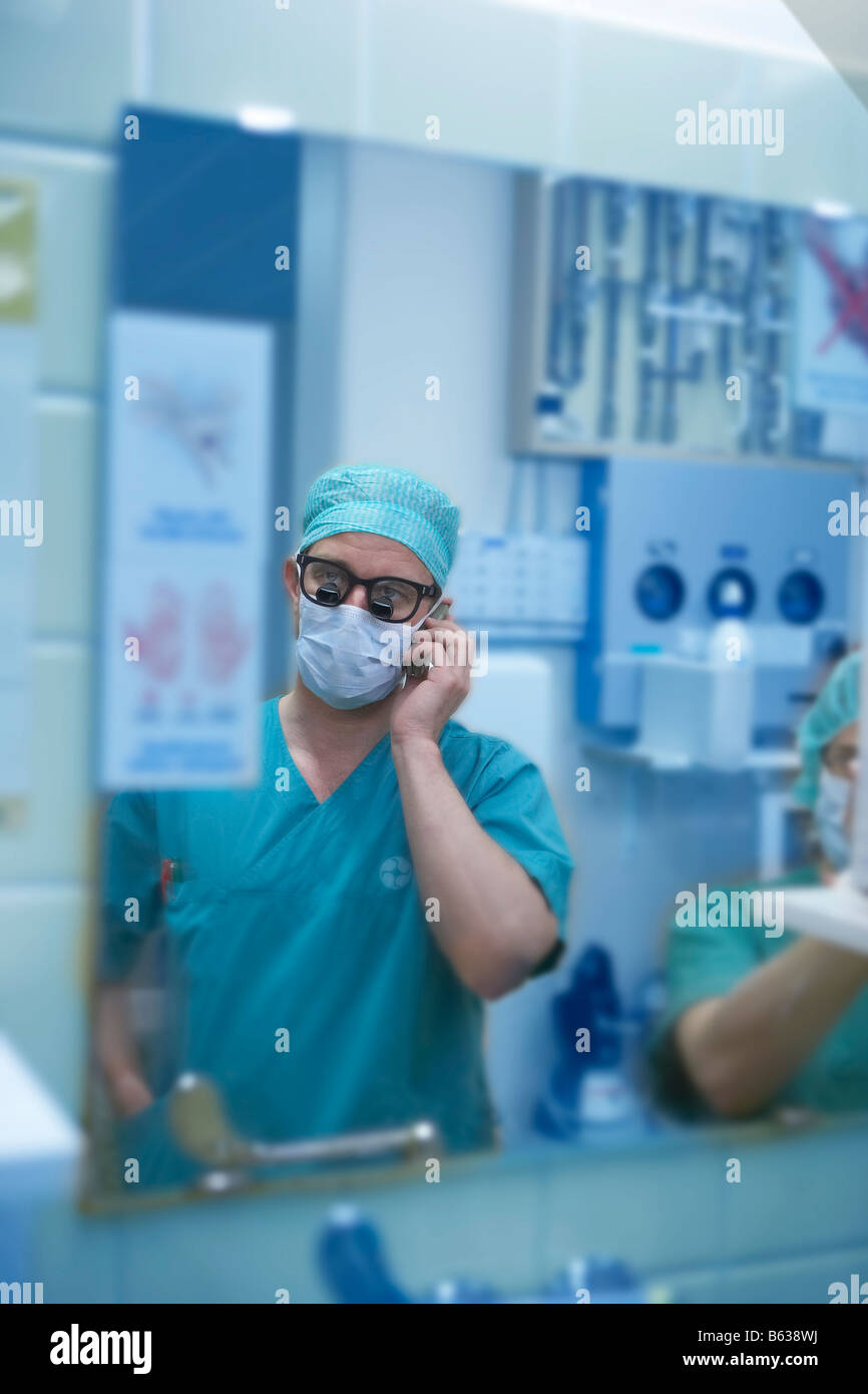 La riflessione di cuore chirurgo indossando occhiali chirurgici tramite telefono cellulare, Reykjavik Islanda Foto Stock