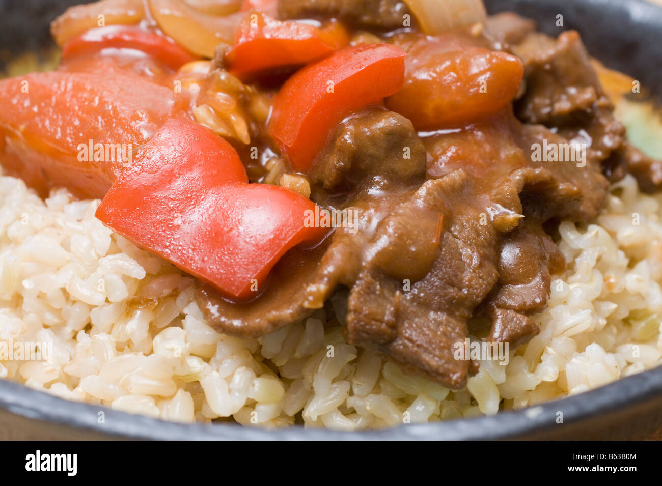 Carni bovine giapponese e pomodoro Stir Fry sul riso marrone Foto Stock