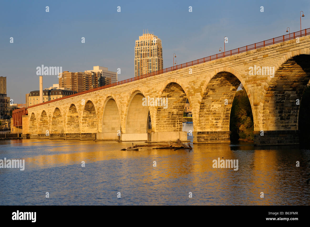 La pietra il ponte di arco riflesso in il bagliore dorato del tramonto sul fiume Mississippi in Minneapolis Minnesota Foto Stock