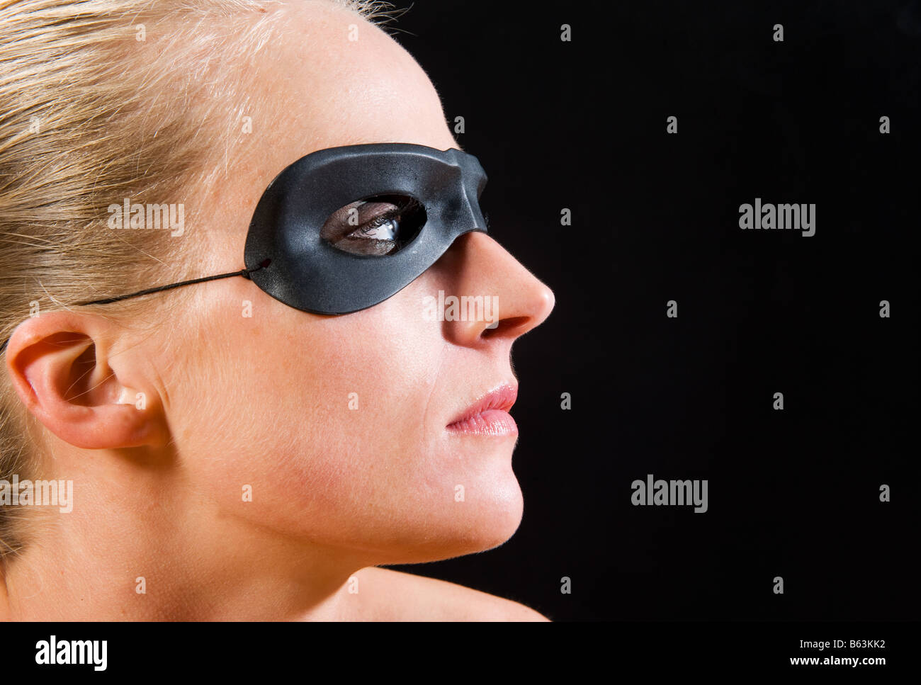 Ragazza bionda che indossa una maschera visto di profilo su sfondo nero Foto Stock
