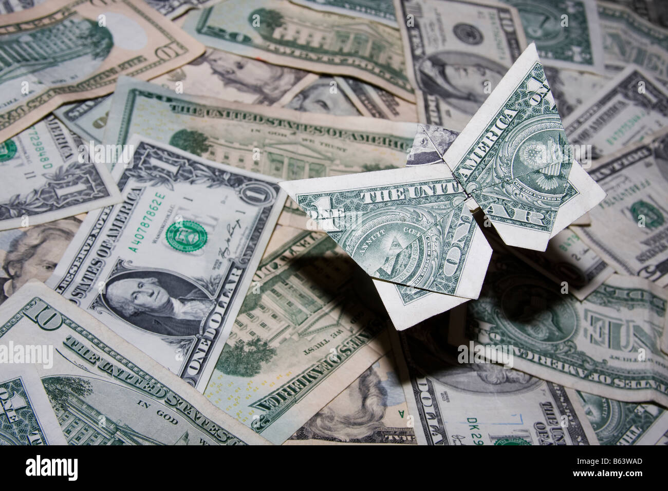 Origami butterfly realizzati al di fuori della valuta statunitense volare sopra un mare di dollari con ombra che rappresentano la perdita di valore e di recessione. Foto Stock